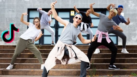 February_2023 Teenagers are dancing in a synchronized manner. The TikTok logo is on the right.