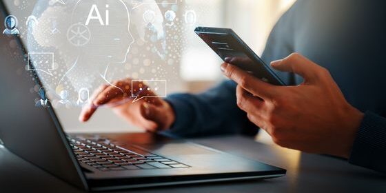 Man is sitting in front of his laptop while holding his phone. AI is written in the top left corner.