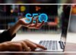 Person on a computer holding the letters SEO.